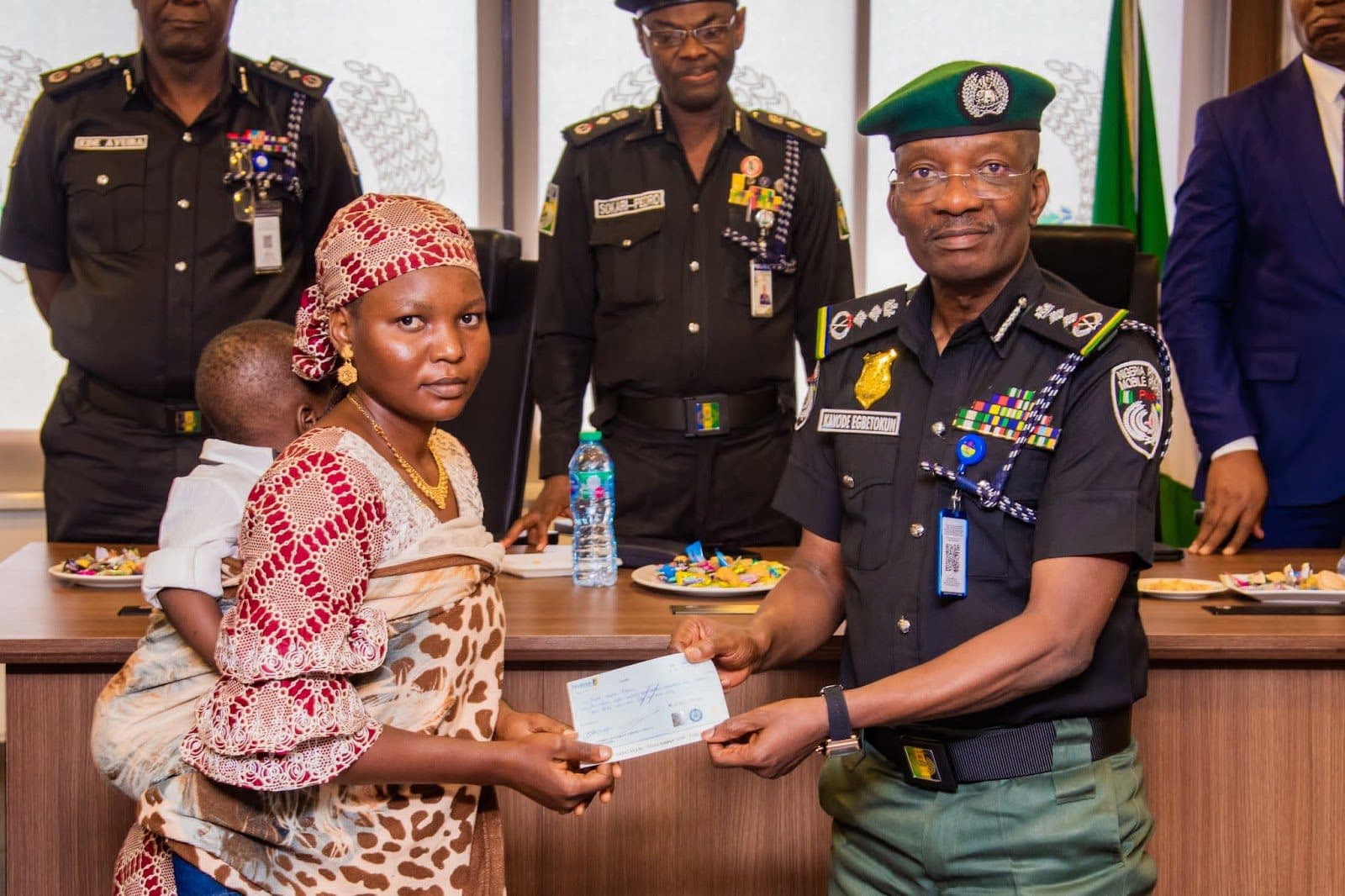 Acting Inspector-General of Police (IGP), Olukayode Egbetokun presenting a cheque to the widow of a slain officer.