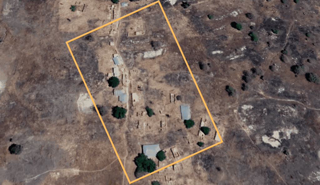 Aerial view of an archaeological site with ruins outlined within an orange perimeter.