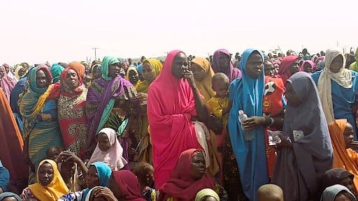 A large group of people in colorful clothing gathered under a hazy sky.