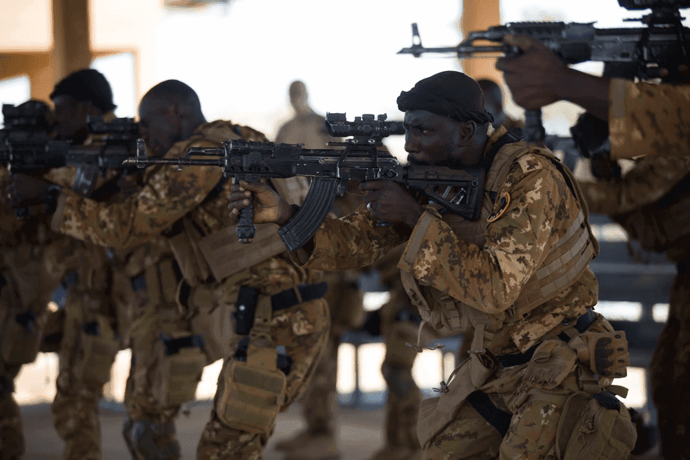 A group of soldiers in camouflage gear aiming their rifles during a training exercise.