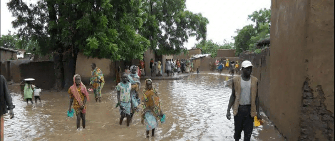 Residents walking through a flooded village street.