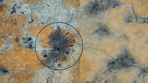 Aerial view of a dense, circular urban area surrounded by arid desert land, showing roadways and sparse vegetation.