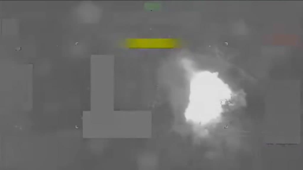 Aerial thermal image showing a bright white explosion against a dark background.