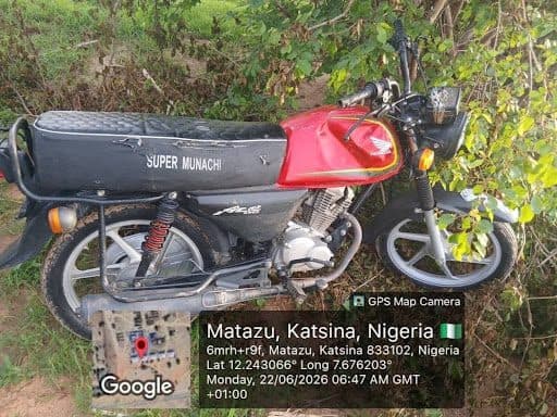 Red and black motorcycle parked on grass, labeled "Super Munachi," with a GPS overlay showing Matazu, Katsina, Nigeria location details.