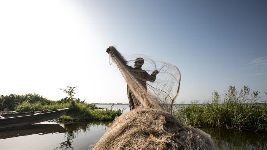 Nigerian Refugee, Hawali Oumar, 43, tidies his fishing net following a night of work.