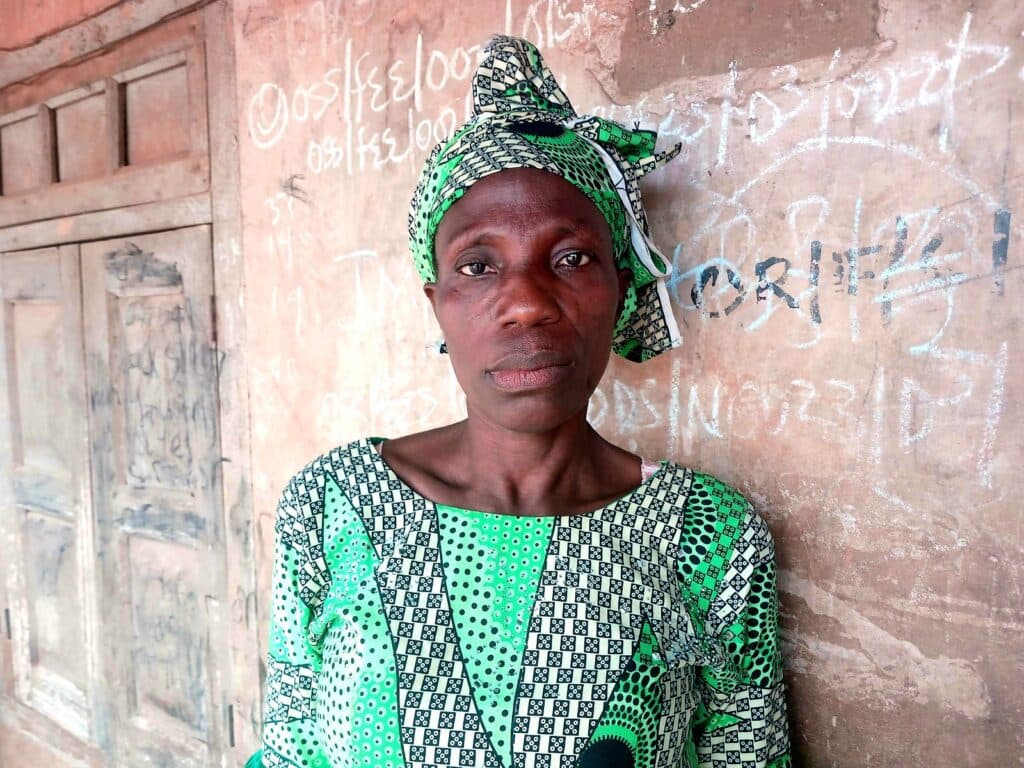 Woman in green patterned attire against a wall with graffiti.