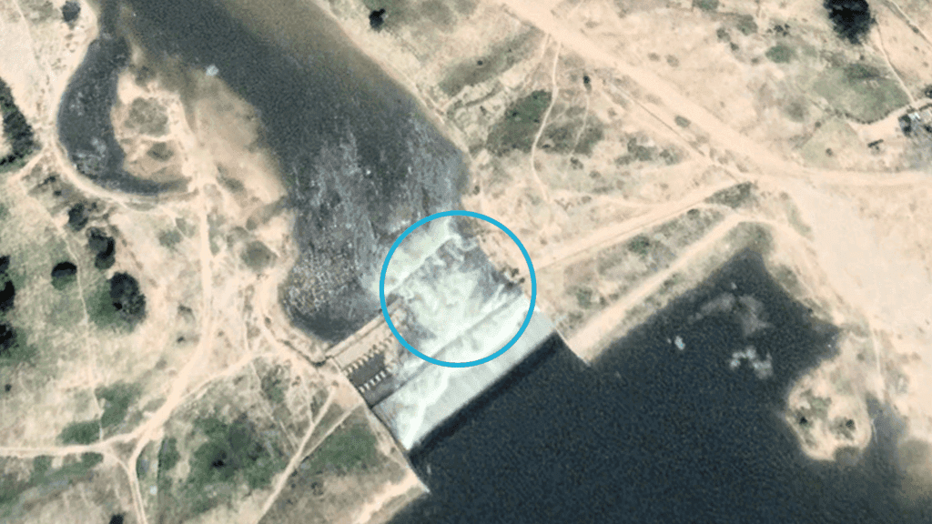 Aerial view of a dam with a highlighted section near water and surrounding terrain.
