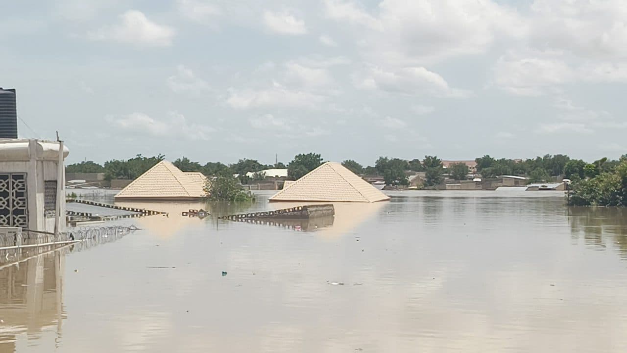 Severe flooding with submerged houses showing only rooftops above water.