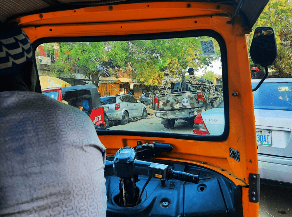 View from inside an auto rickshaw with a busy street scene, including a pickup truck with soldiers.