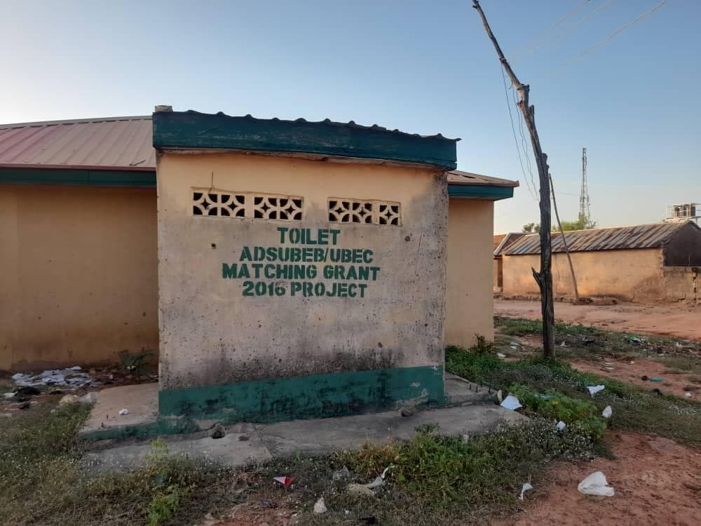 A small public toilet building with a sign indicating it