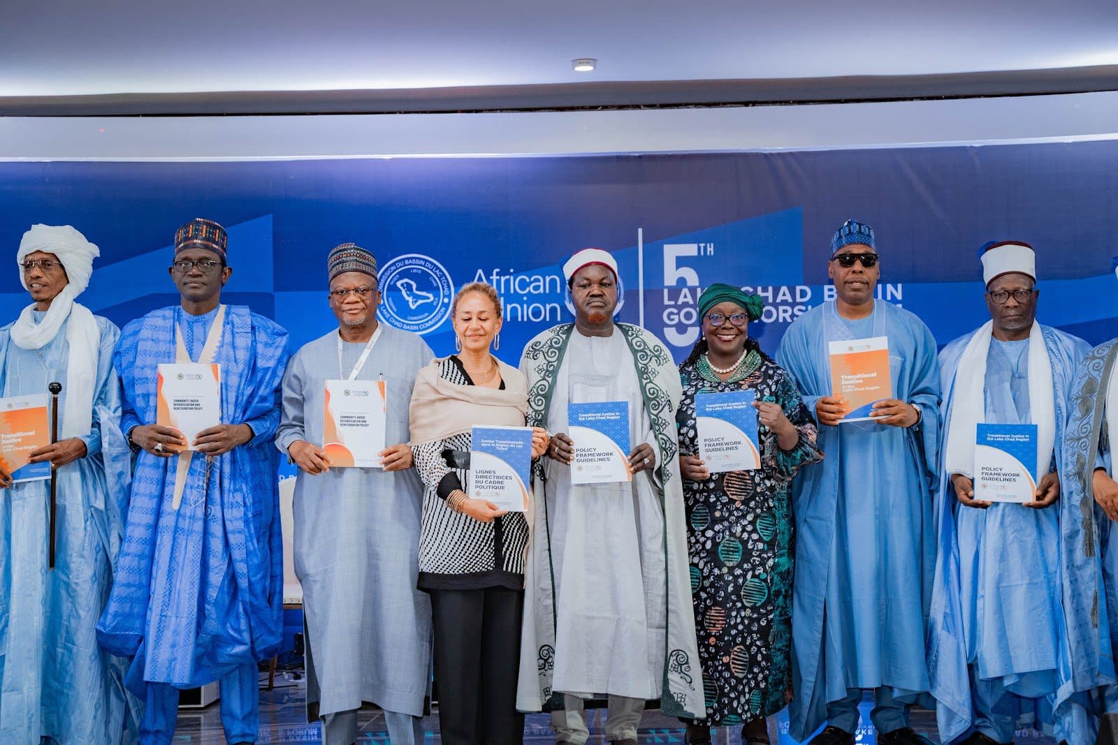 A group of individuals stands holding policy documents at the 5th Lake Chad Basin Governors Forum, African Union backdrop visible.