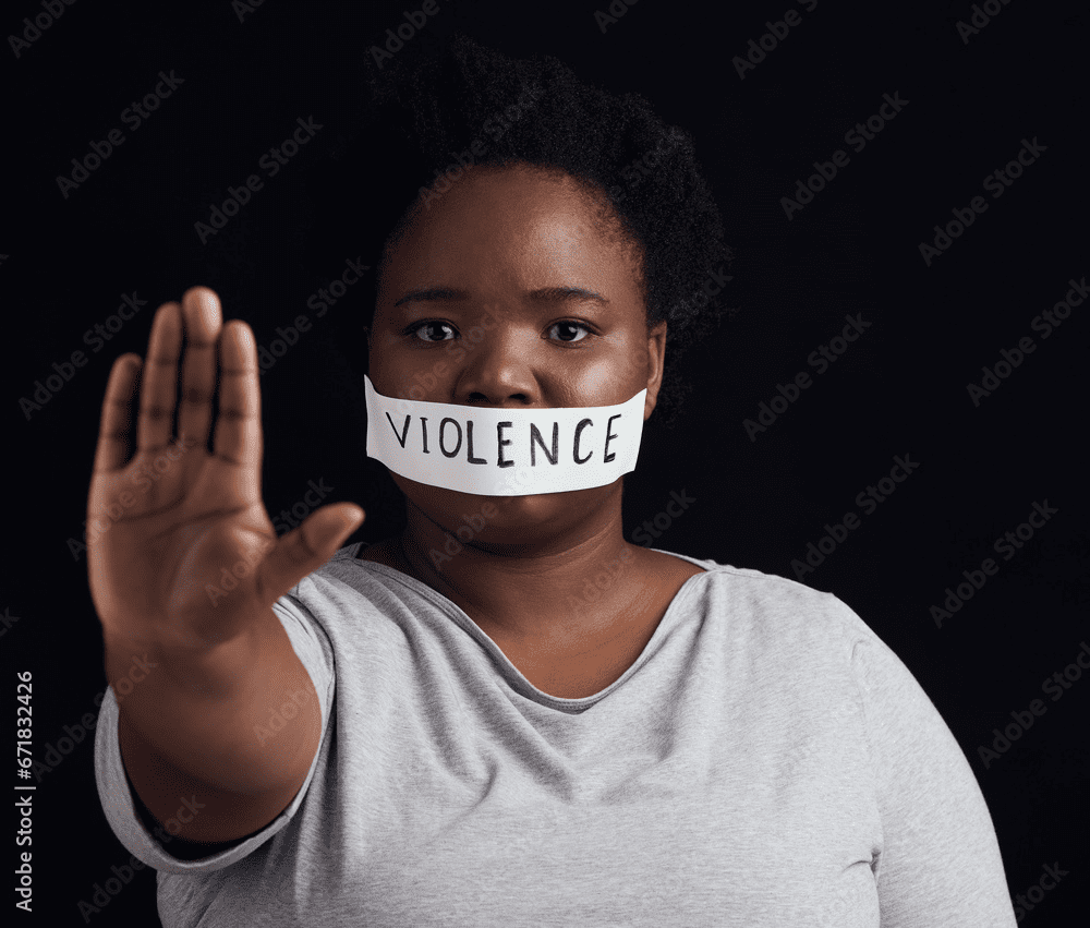 Person with tape labeled "violence" over mouth, holding hand out in a stop gesture against a dark background.