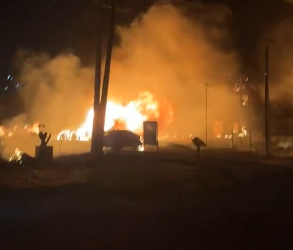 Large fire burning intensely at night, with thick smoke billowing into the dark sky.