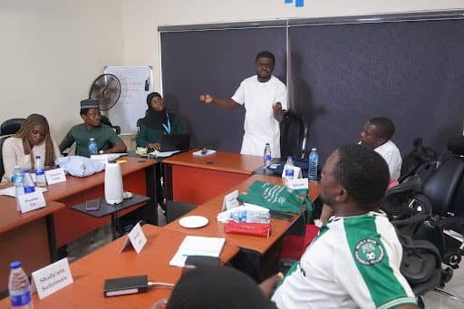 A group of people in discussion around a conference table, one person is speaking while others listen attentively.