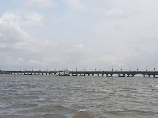 Bridge stretching across a wide river under a cloudy sky.