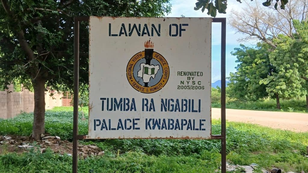 Sign for Lawan of Tumba Ra Ngabili Palace Kwabapale, renovated by NYSC 2005/2006, surrounded by greenery and trees.