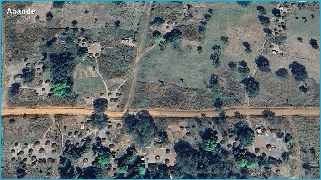 Aerial view of a rural landscape with scattered round huts, trees, and dirt roads in Abande.