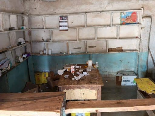 Empty, dusty shop interior with scattered boxes and papers, bare shelves, and a wooden counter in the foreground.