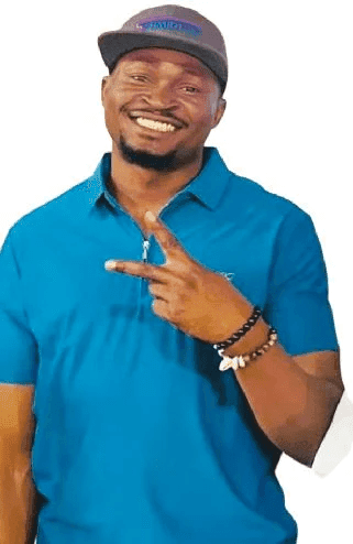 Man in a blue shirt and cap smiling, holding up a peace sign with his right hand.