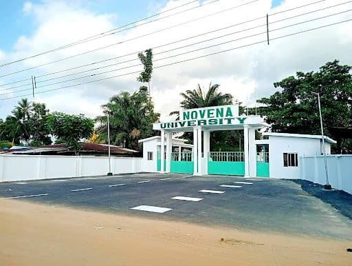 Entrance gate of Novena University with surrounding greenery and clear sky.